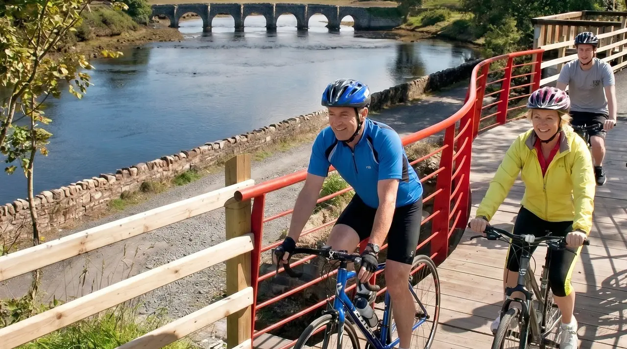 Two cyclists riding a boardwalk beside a river