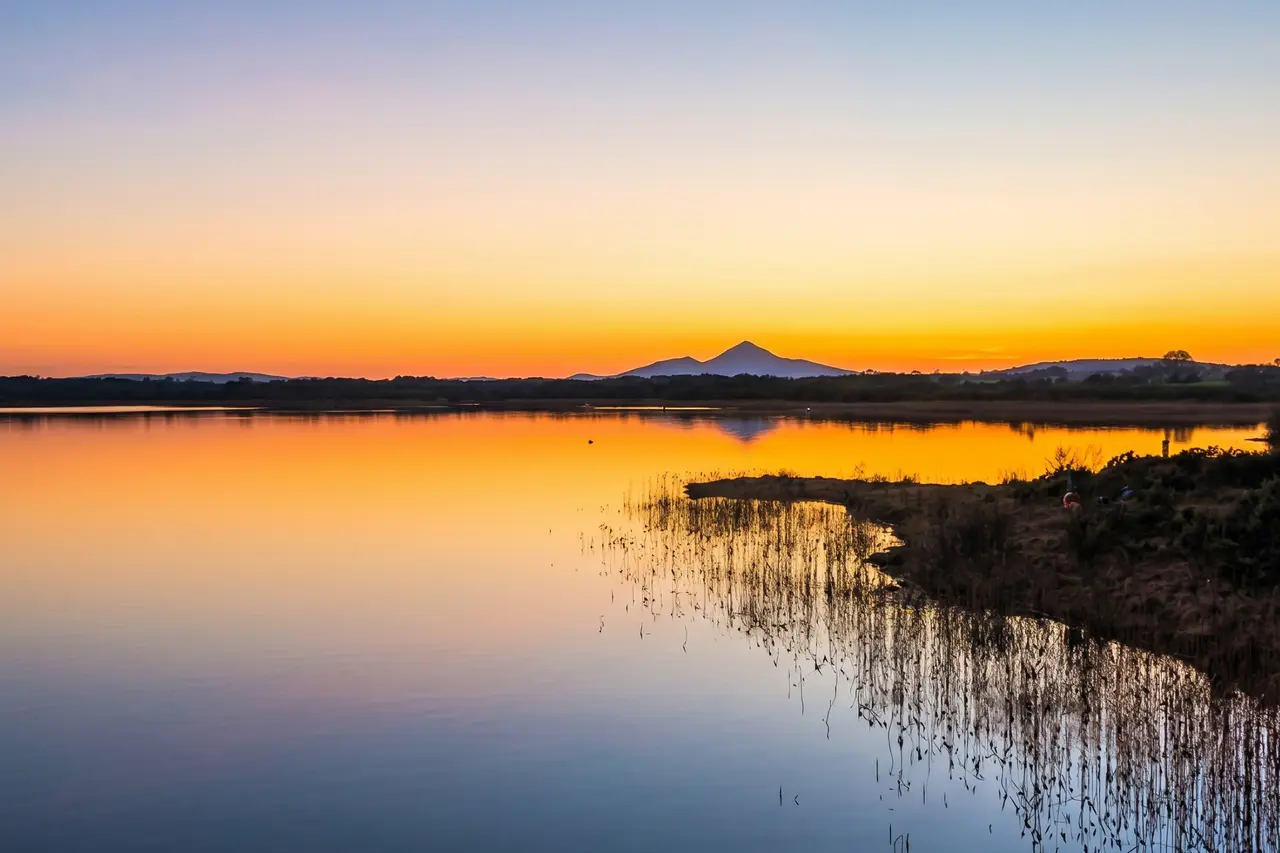 Sunset over a lake with a mountain on the horizon