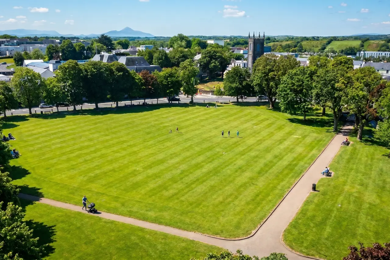 Aerial view of a large town green edged with mature trees